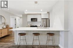 Contemporary kitchen featuring an expansive island with a white countertop and seating for three - 