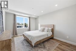 Spacious room featuring a large window, recessed lighting, white trim, and wood-finish flooring - 