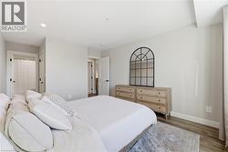 Spacious bedroom featuring light-toned walls, recessed lighting, and wood-finish flooring - 