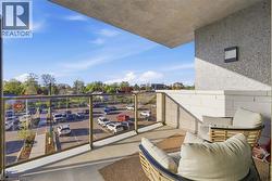 Outdoor balcony featuring concrete flooring, a glass and metal railing, a textured concrete wall, and a built-in wall sconce - 