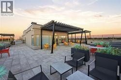 Expansive rooftop terrace featuring large format paver flooring, multiple pergolas, and a perimeter glass railing - 