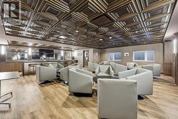 Lounge area featuring a patterned ceiling, wood-finish flooring, and recessed lighting - 