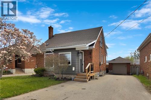 Brick and siding exterior featuring a detached garage, asphalt driveway, and a front porch with wood railings - 371 Ottawa Street S, Kitchener, ON - Outdoor