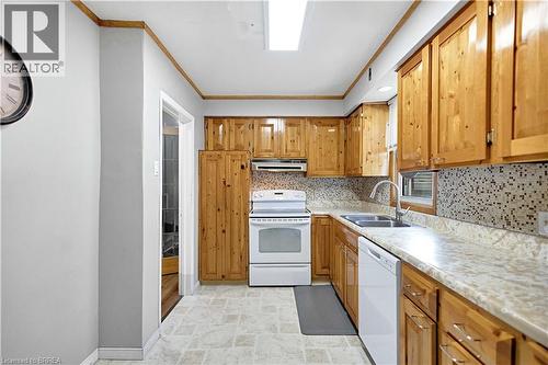 Kitchen featuring wood cabinetry, light-toned countertops, a mosaic tile backsplash, and a white appliance suite - 371 Ottawa Street S, Kitchener, ON - Indoor