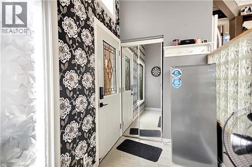 Entryway featuring a white door with decorative glass inserts, patterned wallpaper, a mirrored closet door, glass block partition, and light-colored flooring - 371 Ottawa Street S, Kitchener, ON - Indoor Photo Showing Bathroom