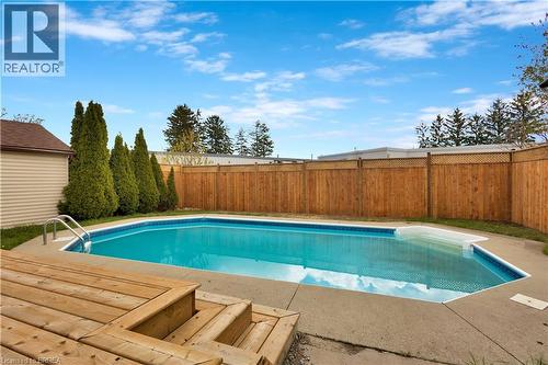 In-ground swimming pool featuring a concrete surround, wood-finish decking, and an adjacent utility shed - 371 Ottawa Street S, Kitchener, ON - Outdoor With In Ground Pool With Backyard