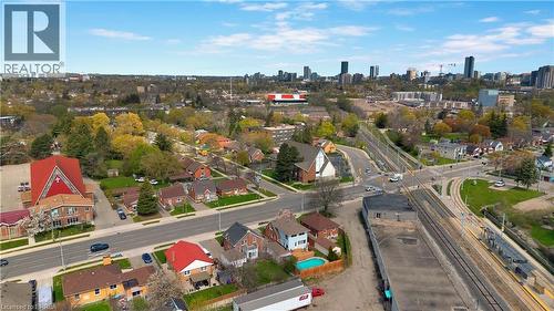 Aerial perspective showcasing a mixed-use urban landscape with residential homes, mature trees, commercial buildings, and a distant city skyline - 371 Ottawa Street S, Kitchener, ON - Outdoor With View
