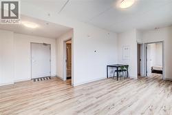 Spacious interior with light wood-finish flooring, white walls, and flush-mount ceiling lights - 