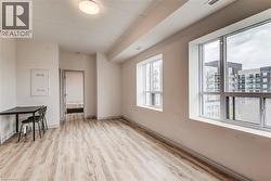 Spacious room featuring wood-finish flooring, white walls, and multiple large windows - 