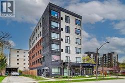 Modern multi-story building featuring a facade of dark brick, light-colored panels, and exposed red brickwork - 