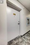 White entry door with polished chrome hardware and a brass-toned unit number - 