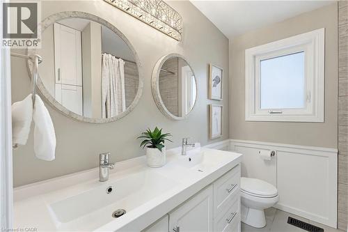 Contemporary bathroom featuring a double vanity with integrated sinks, two circular mirrors, and a modern light fixture - 60 Avenue Road, Cambridge, ON - Indoor Photo Showing Bathroom