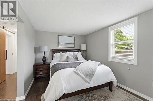 Neutral-toned bedroom featuring dark wood-finish flooring, a white window frame with blinds, and light gray walls - 60 Avenue Road, Cambridge, ON - Indoor Photo Showing Bedroom