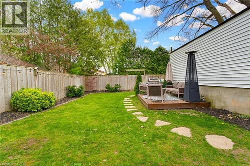 Private backyard featuring a wooden privacy fence with string lighting, mature landscaping, a stone paver pathway, and a wooden deck - 60 Avenue Road, Cambridge, ON - Outdoor