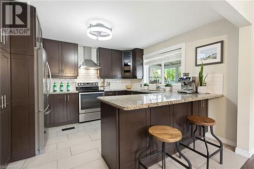 Kitchen featuring dark wood-finish cabinetry, stainless steel appliances, a tile backsplash, and light-toned tile flooring - 60 Avenue Road, Cambridge, ON - Indoor Photo Showing Kitchen With Stainless Steel Kitchen With Upgraded Kitchen