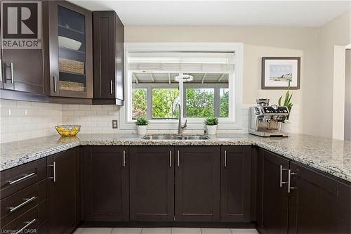 U-shaped kitchen with dark wood cabinetry, light speckled countertops, white subway tile backsplash, and a double basin stainless steel sink - 60 Avenue Road, Cambridge, ON - Indoor Photo Showing Kitchen With Double Sink With Upgraded Kitchen