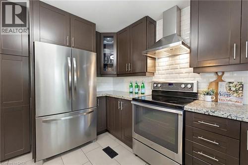 Modern kitchen featuring dark wood-finish cabinetry, stainless steel appliances, granite countertops, and a white subway tile backsplash - 60 Avenue Road, Cambridge, ON - Indoor Photo Showing Kitchen With Stainless Steel Kitchen With Upgraded Kitchen