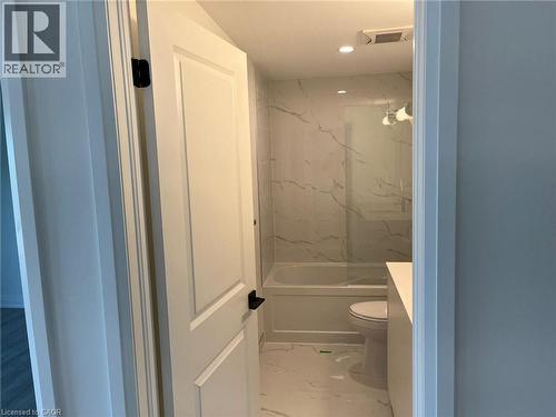 Contemporary bathroom featuring a tub-shower combination with full-height veined wall tile, a glass shower panel, and recessed lighting - 3370 Stella Crescent Unit# 235, Windsor, ON - Indoor Photo Showing Bathroom