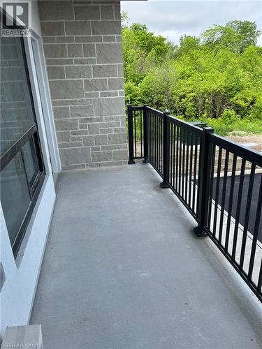 Concrete balcony with black metal railing, featuring a stone veneer wall and large window - 3370 Stella Crescent Unit# 235, Windsor, ON - Outdoor With Balcony With Exterior