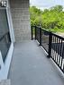 Concrete balcony with black metal railing, featuring a stone veneer wall and large window - 3370 Stella Crescent Unit# 235, Windsor, ON  - Outdoor With Balcony With Exterior 