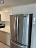 Stainless steel French door refrigerator set against white upper cabinetry and wood-finish lower cabinetry - 3370 Stella Crescent Unit# 235, Windsor, ON  - Indoor Photo Showing Kitchen 