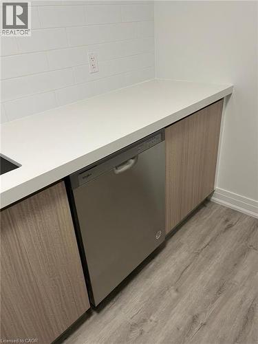 Stainless steel dishwasher integrated into modern cabinetry with wood-finish doors - 3370 Stella Crescent Unit# 235, Windsor, ON - Indoor Photo Showing Other Room