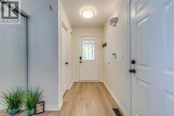 Entryway featuring light wood-finish flooring, white trim, and a frosted glass front door - 