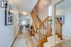 Open concept entryway featuring wood-finish flooring, a carpeted staircase with wood banister, and a mirrored closet - 