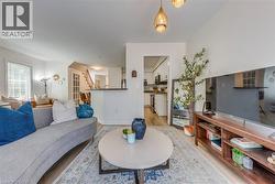 Open-concept living space featuring wood-finish flooring, white walls, recessed lighting, and a kitchen pass-through with a breakfast bar - 