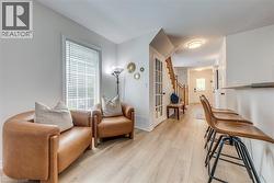 Light wood-finish flooring extending throughout, white walls, and a staircase with natural wood railings - 