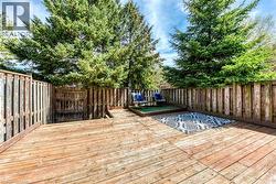 Expansive wood deck with a tiered design, featuring a private fenced perimeter, mature evergreen trees, and an elevated platform area - 
