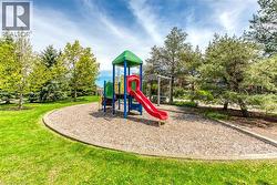 Community playground featuring a composite play structure with a slide, a wood chip surface, and a surrounding lawn - 