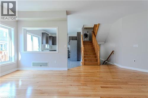 Open concept living space featuring wood-finish flooring, light grey wall paint, and a pass-through window to the kitchen - 3896 Tufgar Crescent, Burlington, ON - Indoor Photo Showing Other Room