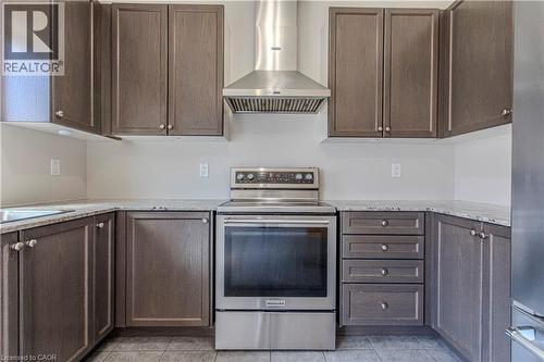 Kitchen featuring dark wood-finish cabinetry, light-toned countertops, stainless steel appliances, and a tile floor - 3896 Tufgar Crescent, Burlington, ON - Indoor Photo Showing Kitchen