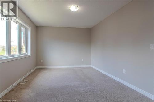 Carpeted room featuring neutral wall paint, white trim, a large multi-pane window, and a ceiling-mounted light fixture - 3896 Tufgar Crescent, Burlington, ON - Indoor Photo Showing Other Room