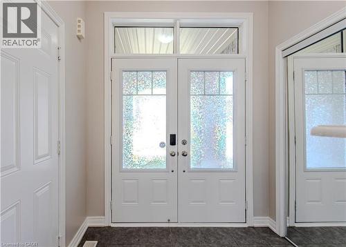 Double entry doors with patterned glass inserts and a transom window, complemented by dark tile flooring and light-toned walls - 3896 Tufgar Crescent, Burlington, ON - Indoor Photo Showing Other Room