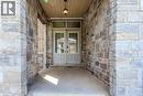 Inviting entryway featuring stone facade, dual entry doors with transom window, and a covered porch with a recessed ceiling and pendant lighting - 3896 Tufgar Crescent, Burlington, ON  - Outdoor With Exterior 