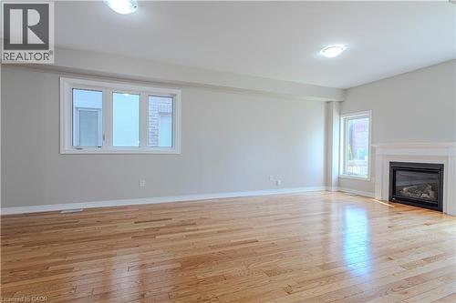 Spacious interior featuring wood-finish flooring, a contemporary fireplace with a white mantel, and multiple windows - 3896 Tufgar Crescent, Burlington, ON - Indoor Photo Showing Living Room With Fireplace