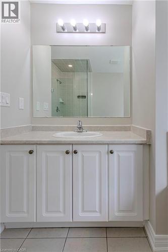 Bathroom vanity featuring an integrated sink, laminate countertop, white paneled cabinetry with dark hardware, a large mirror, and overhead strip lighting - 3896 Tufgar Crescent, Burlington, ON - Indoor Photo Showing Bathroom