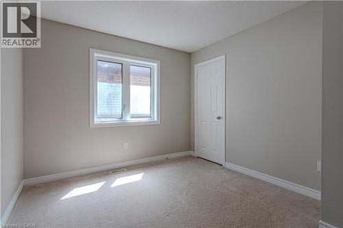 Carpeted room featuring a white-framed window, neutral painted walls, white trim, and a paneled interior door - 3896 Tufgar Crescent, Burlington, ON - Indoor Photo Showing Other Room