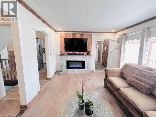 Living area featuring a floor-to-ceiling fireplace with wood paneling and a stone-look surround - 56 Eastvale Place, Hamilton, ON - Indoor Photo Showing Living Room With Fireplace