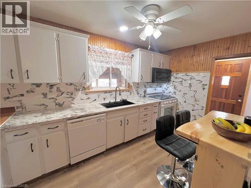 Kitchen featuring white cabinetry with dark hardware, a black sink, and a contrasting white and gray tile backsplash - 56 Eastvale Place, Hamilton, ON - Indoor Photo Showing Kitchen