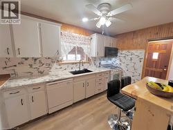 Kitchen featuring white cabinetry with dark hardware, a black sink, and a contrasting white and gray tile backsplash - 