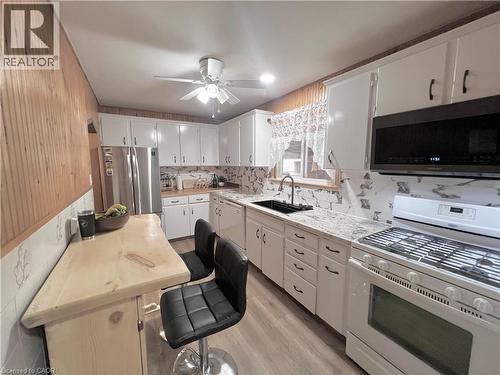 Kitchen featuring white cabinetry, light-toned countertops, a black sink with a matte black faucet, and a white gas range - 56 Eastvale Place, Hamilton, ON - Indoor Photo Showing Kitchen