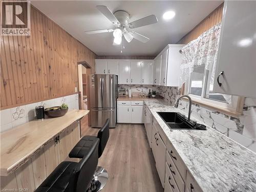 Well-appointed kitchen featuring wood-finish flooring and a wood-paneled accent wall - 56 Eastvale Place, Hamilton, ON - Indoor Photo Showing Kitchen With Double Sink