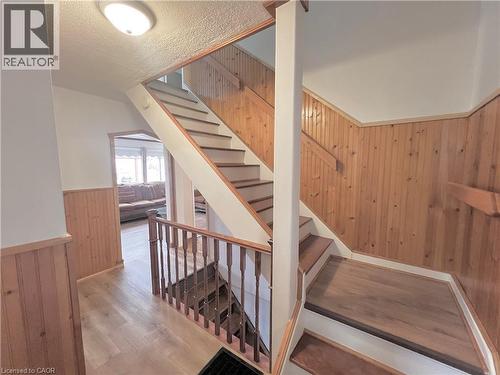 Two-story staircase featuring wood-finish treads and risers, wood paneled walls, and a matching wood-finish handrail and balusters - 56 Eastvale Place, Hamilton, ON - Indoor Photo Showing Other Room