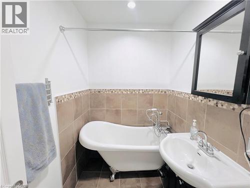 Bathroom featuring a clawfoot tub, a pedestal sink with chrome fixtures, and a dark wood-finish medicine cabinet - 56 Eastvale Place, Hamilton, ON - Indoor Photo Showing Bathroom