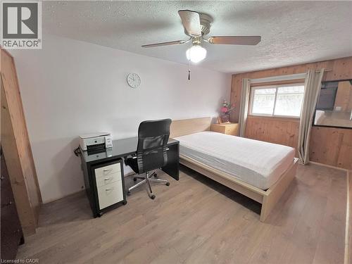 Room featuring wood-finish flooring, a ceiling fan with integrated lighting, and a wall of horizontal wood paneling - 56 Eastvale Place, Hamilton, ON - Indoor Photo Showing Bedroom