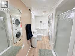 Full bathroom featuring a shower stall with clear glass, wood-finish flooring, and a white toilet - 