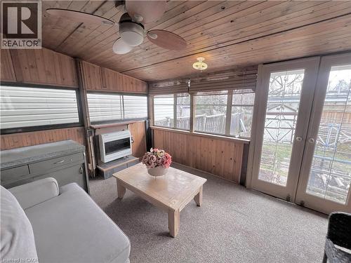 Sunroom featuring wood-paneled walls and ceiling, multiple windows, a ceiling fan with integrated lighting, and double glass doors - 56 Eastvale Place, Hamilton, ON - Indoor